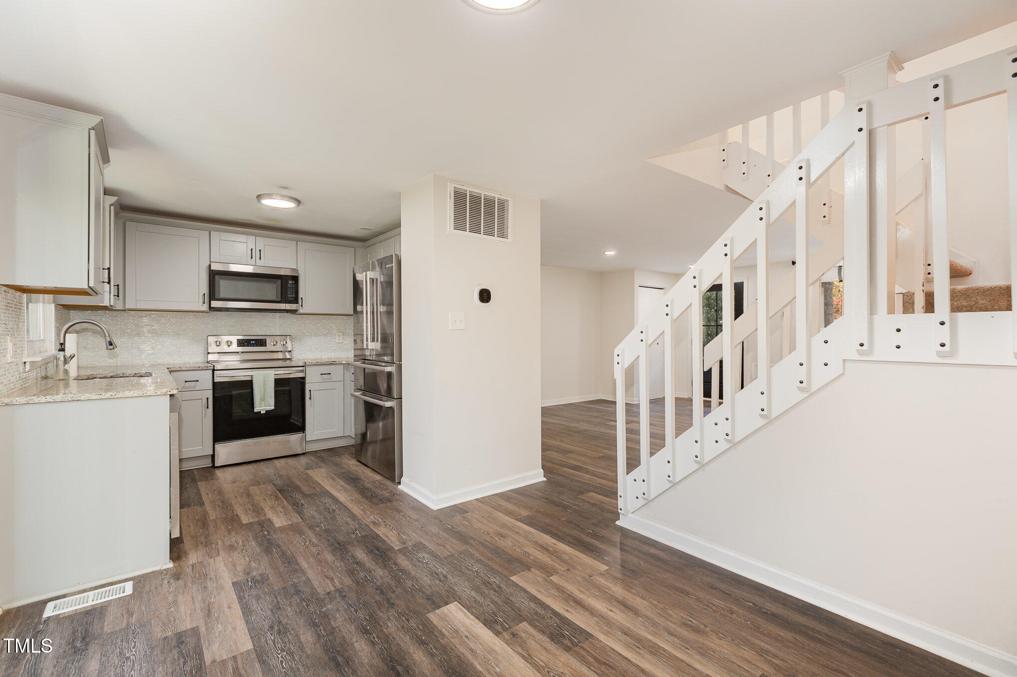 7324 Summerland Drive Raleigh, NC 27612 - Photo 6 of 24 a kitchen with granite countertop a refrigerator oven a sink dishwasher and white cabinets with wooden floor