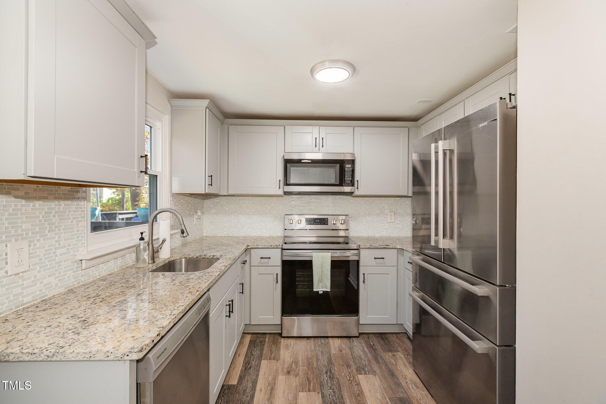 7324 Summerland Drive Raleigh, NC 27612 - Photo 7 of 24 a kitchen with stainless steel appliances granite countertop a sink stove microwave and refrigerator