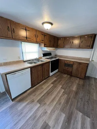 a kitchen with stainless steel appliances granite countertop a sink a stove a refrigerator cabinets and wooden floor