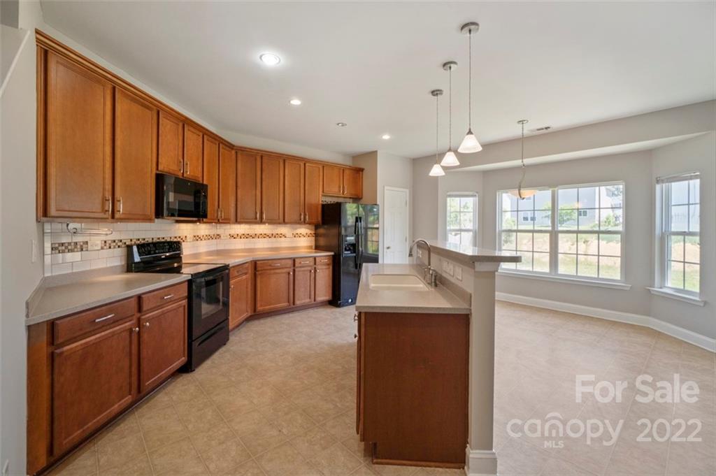 4416 Marys Point Road Monroe, NC 28110 - Photo 6 of 33 a kitchen with stainless steel appliances granite countertop a stove top oven a sink dishwasher and a refrigerator with wooden floor
