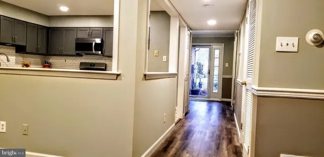 a view of a kitchen with a refrigerator a stove top oven and wooden floor