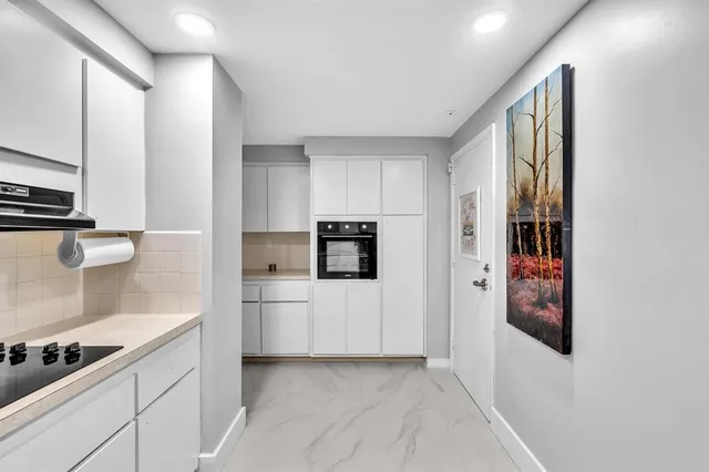 a kitchen with stainless steel appliances a sink a stove and white cabinets