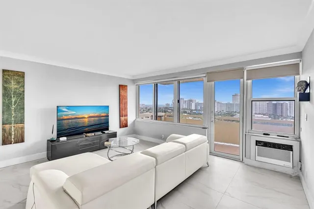 a living room with furniture a flat screen tv and a floor to ceiling window