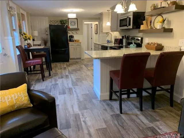 a kitchen with stainless steel appliances granite countertop a refrigerator a stove a sink dishwasher and a microwave with wooden floor