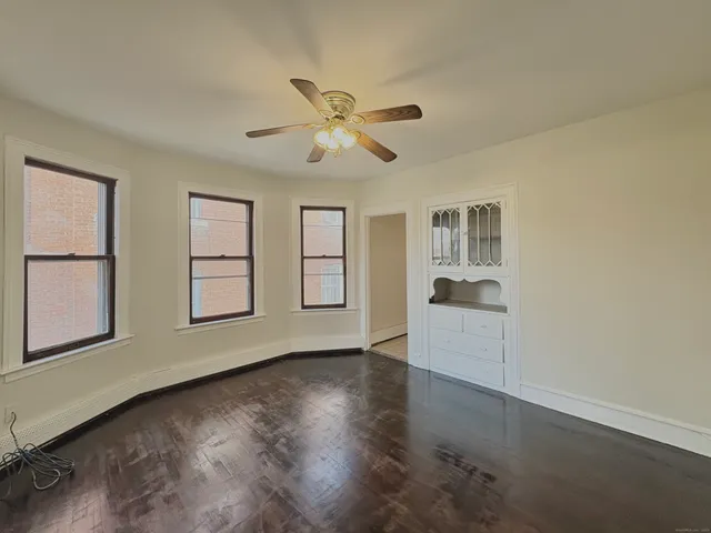 a view of an empty room with a window and wooden floor