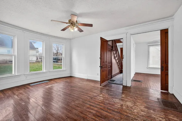 a view of an empty room with wooden floor and a window