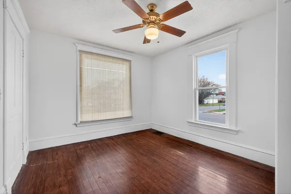 a view of an empty room with wooden floor and a window