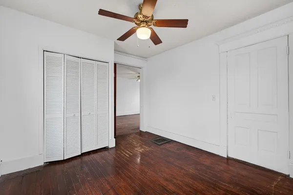 an empty room with wooden floor fan and windows