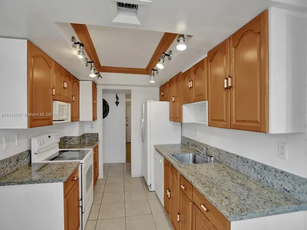 a kitchen with granite countertop a sink a counter top space cabinets and stainless steel appliances