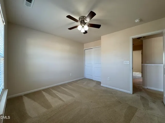 an empty room with closet and ceiling fan