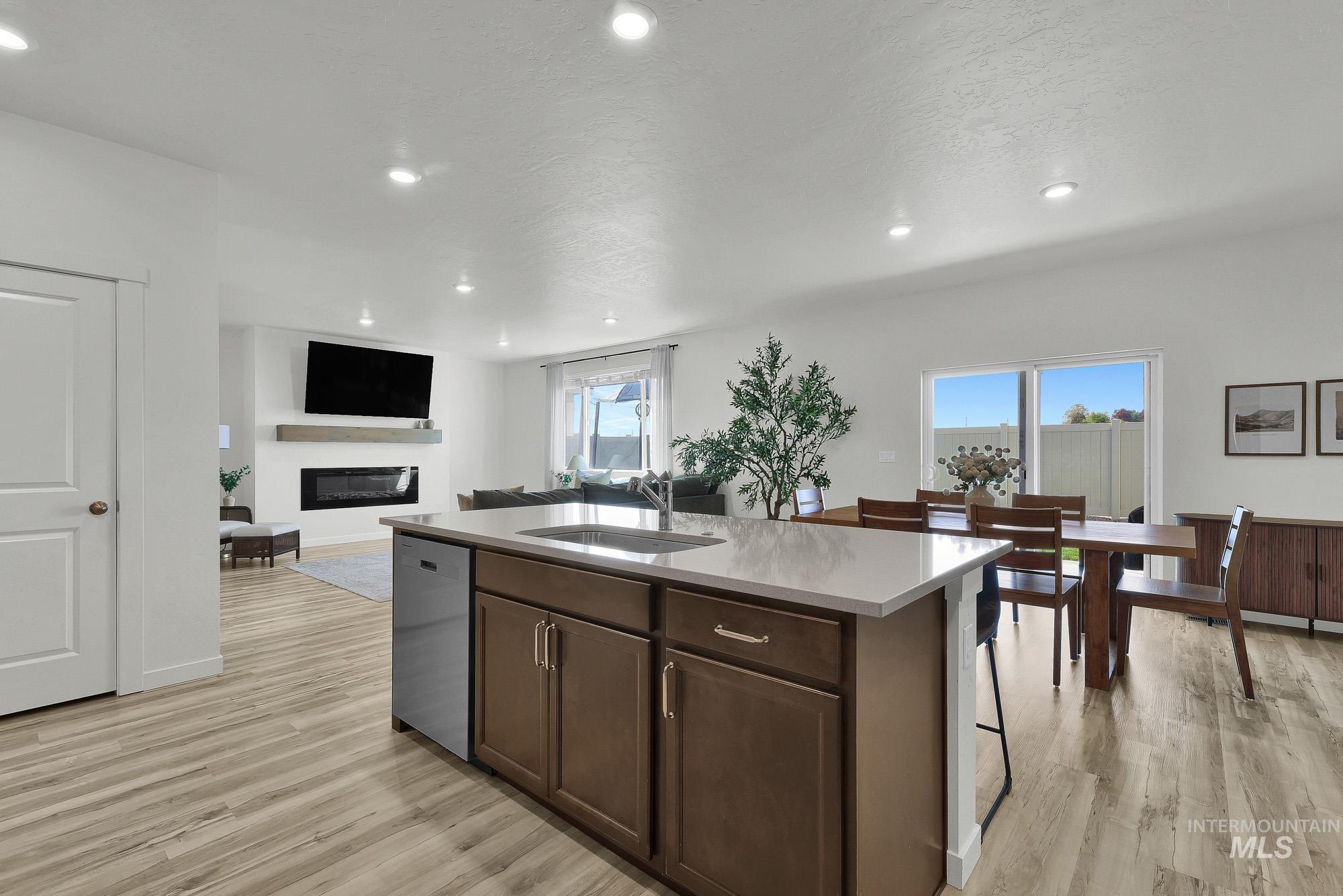 717 West Lyra Street Meridian, ID 83642 - Photo 15 of 50 Kitchen island with integrated sink and dishwasher, featuring wood-finish cabinetry and light-toned countertop