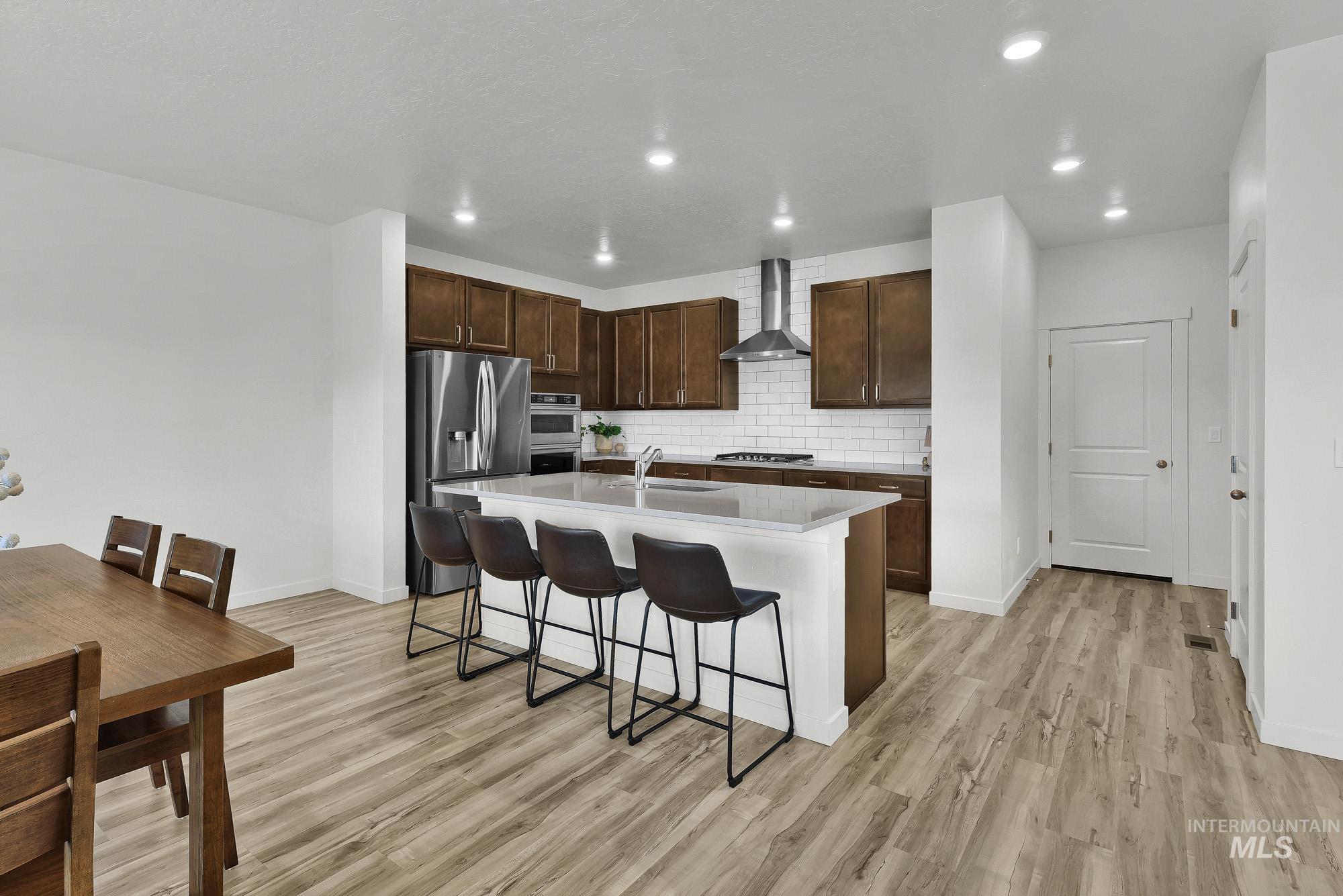 717 West Lyra Street Meridian, ID 83642 - Photo 16 of 50 Open-concept kitchen with dark wood cabinetry, stainless steel appliances, and a central island with countertop seating