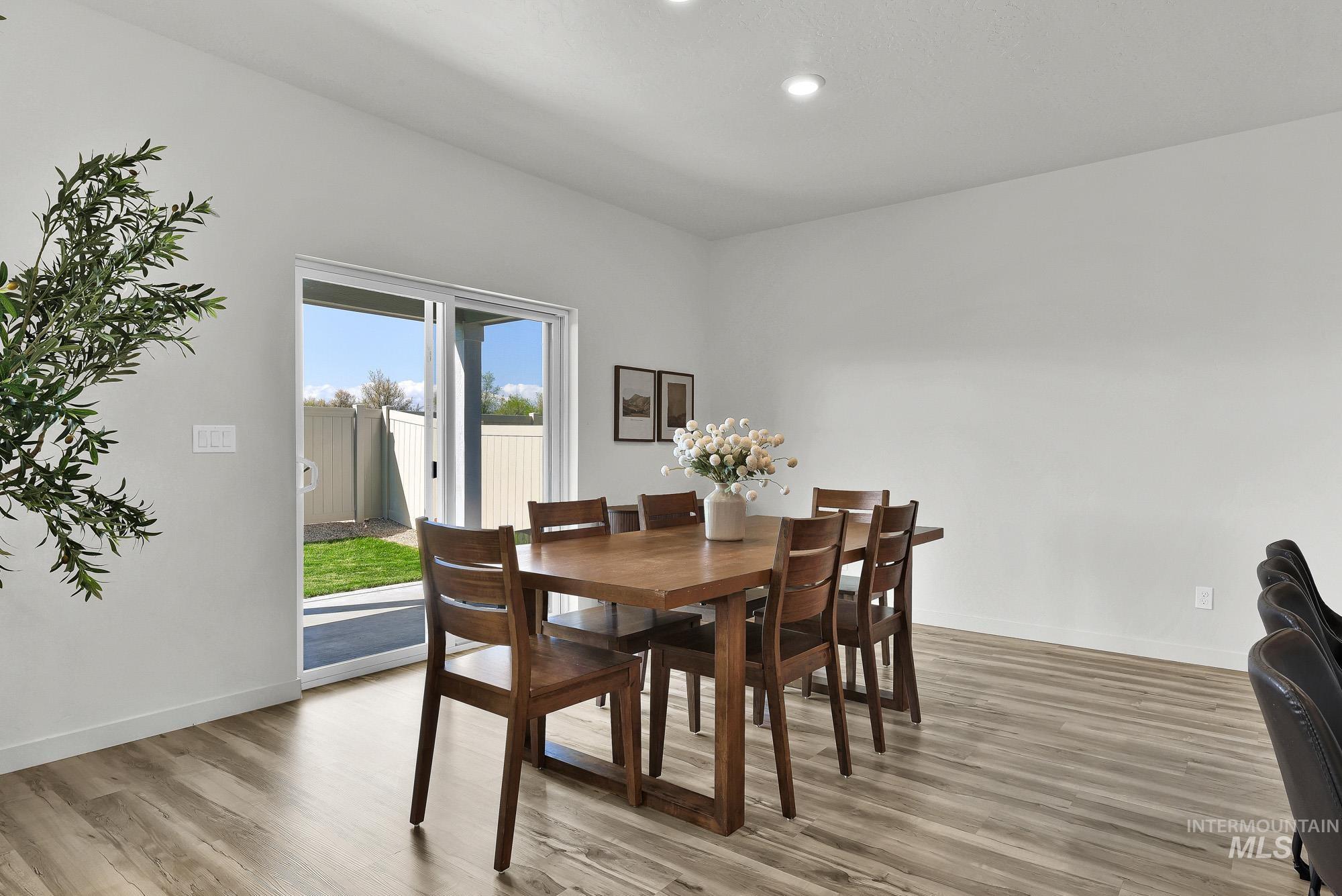 717 West Lyra Street Meridian, ID 83642 - Photo 19 of 50 Open-concept dining area featuring wood-finish flooring, a contemporary ceiling light fixture, and a sliding glass door providing direct access to the backyard