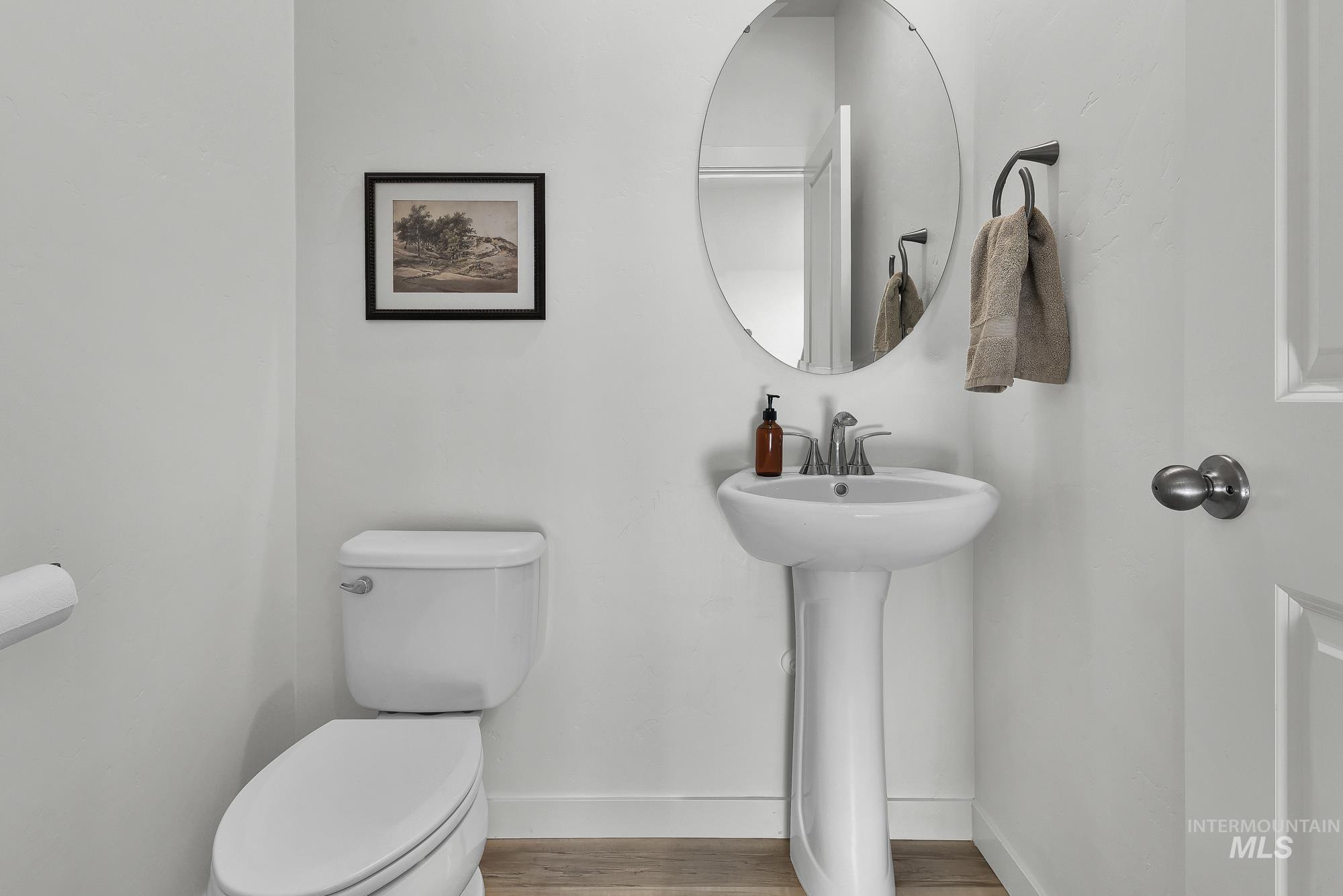 717 West Lyra Street Meridian, ID 83642 - Photo 20 of 50 Pedestal sink with chrome faucet, oval mirror, and wood-finish flooring