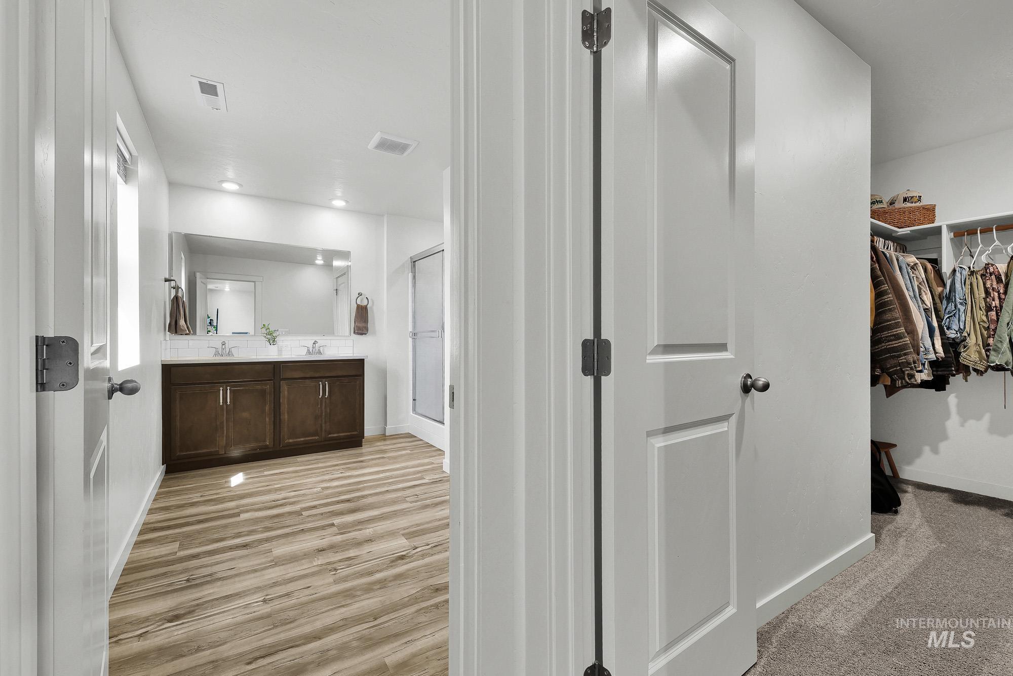717 West Lyra Street Meridian, ID 83642 - Photo 29 of 50 Bathroom entry featuring a dual vanity with dark wood cabinetry, light-toned countertops, and a large mirror