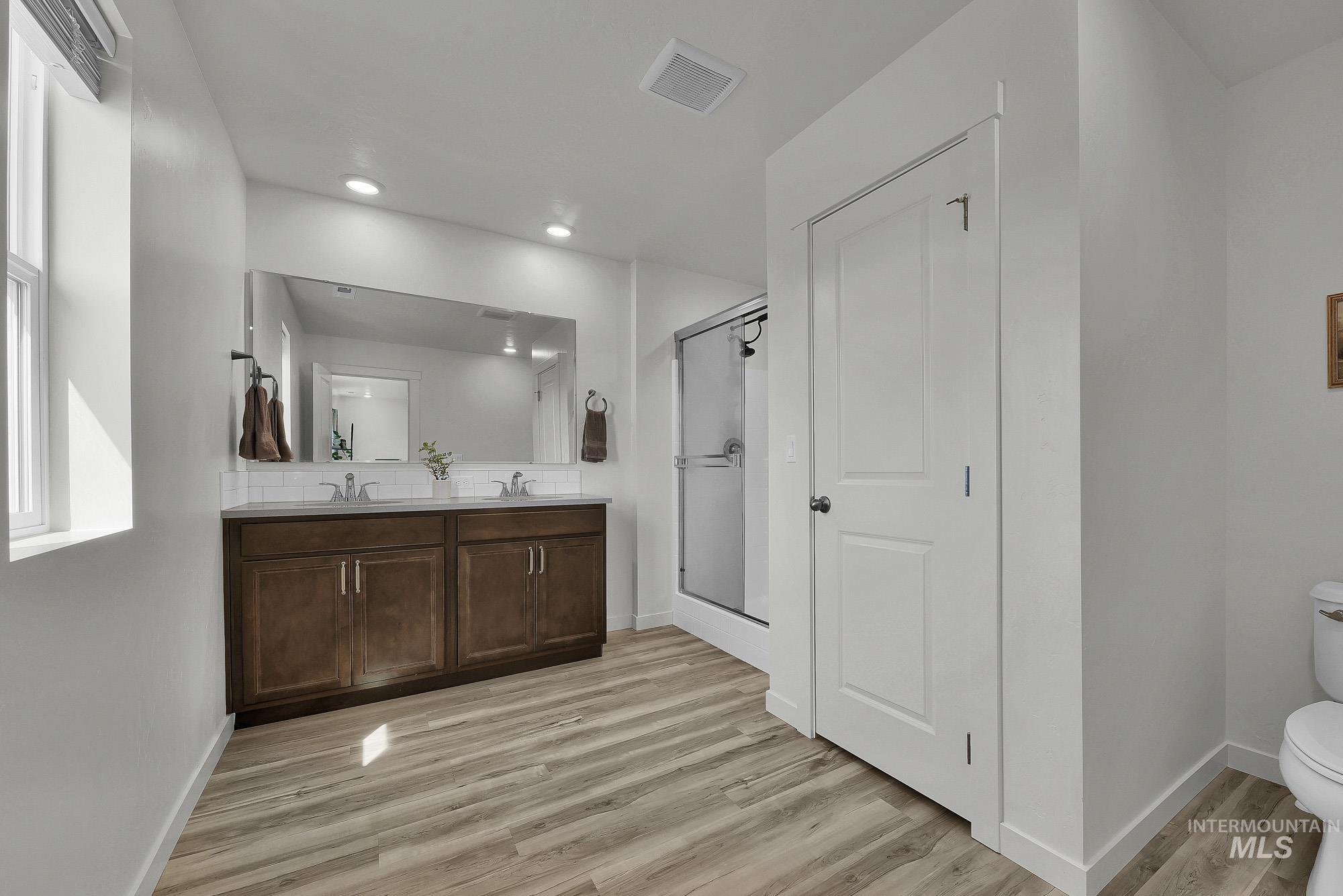 717 West Lyra Street Meridian, ID 83642 - Photo 30 of 50 Bathroom featuring a double vanity with wood-finish cabinetry, a large frameless mirror, and dual undermount sinks