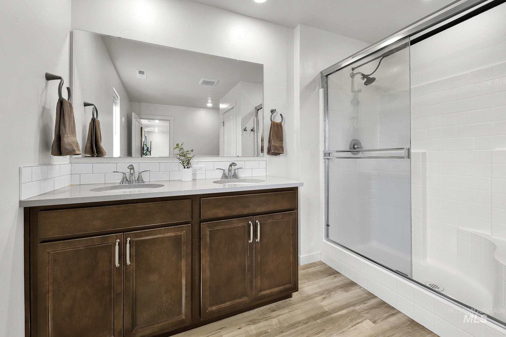 717 West Lyra Street Meridian, ID 83642 - Photo 32 of 50 Bathroom featuring a dual vanity with dark wood-finish cabinetry, light countertops, and a full-width mirror
