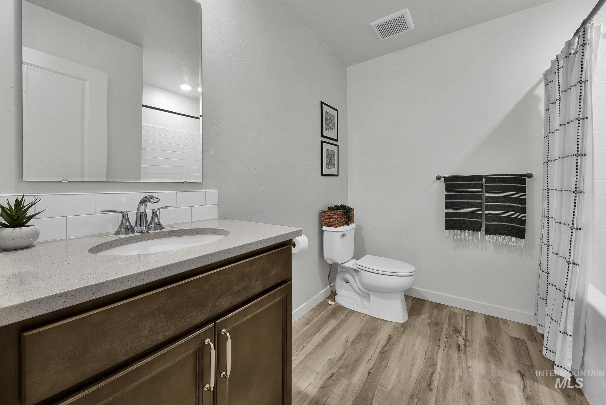 717 West Lyra Street Meridian, ID 83642 - Photo 41 of 50 Full bathroom featuring a wood-finish vanity with a light-colored countertop, an undermount sink, and a subway tile backsplash
