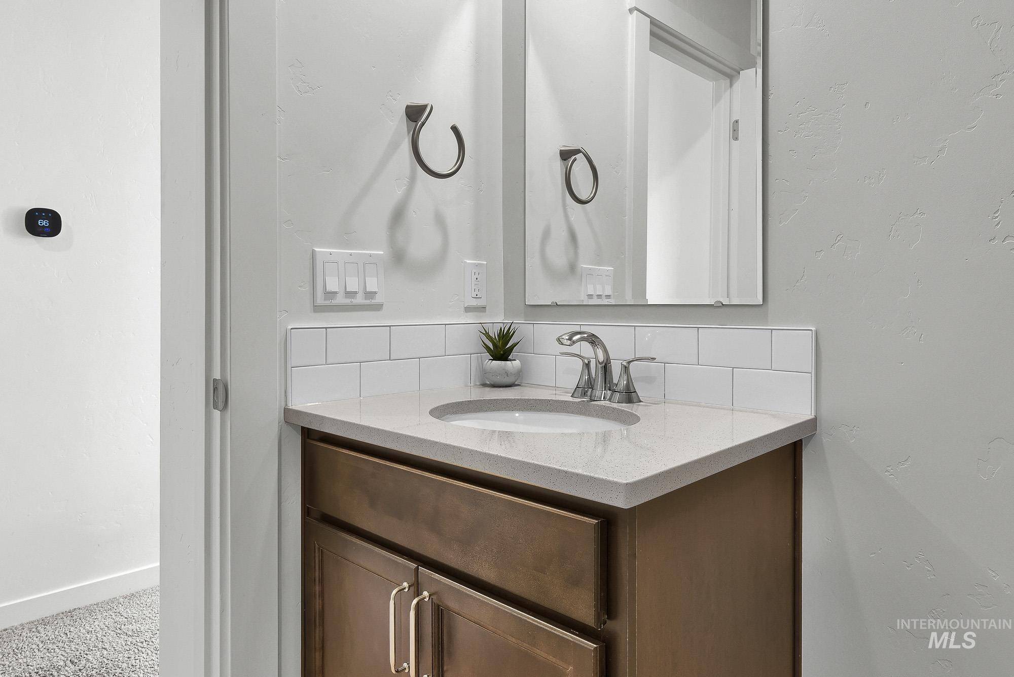 717 West Lyra Street Meridian, ID 83642 - Photo 42 of 50 Bathroom vanity featuring a light-toned countertop, undermount sink, and dark wood-finish cabinetry with brushed metal hardware