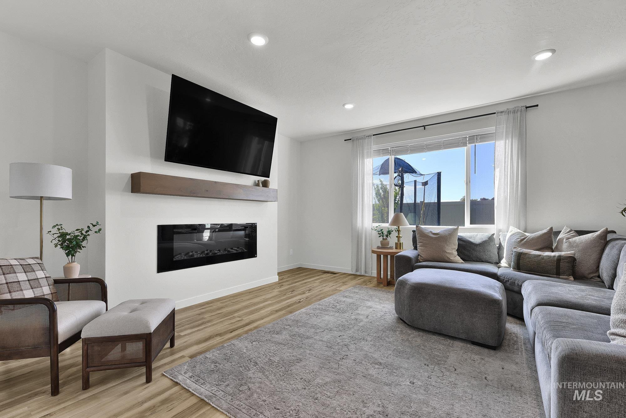 717 West Lyra Street Meridian, ID 83642 - Photo 7 of 50 Living area featuring a modern linear fireplace with a wood mantel, recessed lighting, wood-finish flooring, and a large window