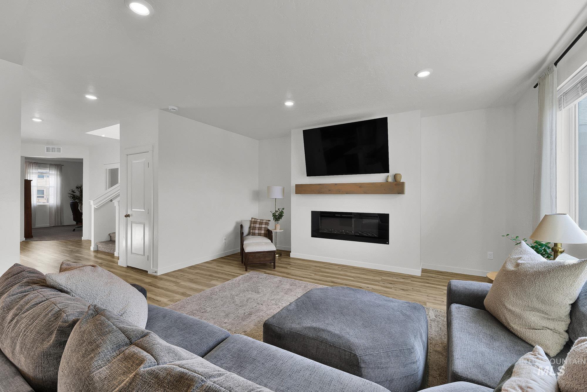 717 West Lyra Street Meridian, ID 83642 - Photo 9 of 50 Living area featuring a built-in electric fireplace with a wood mantel, recessed lighting, and wood-finish flooring