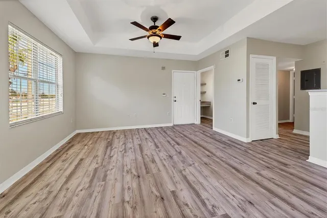 a view of empty room with wooden floor and fan