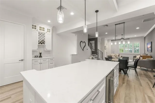 a large kitchen with kitchen island a stove a sink a dining table and chairs with wooden floor