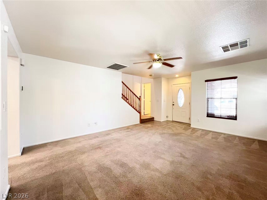 11143 Ranch Valley Street Las Vegas, NV 89179 - Photo 3 of 23 A spacious living room featuring soft carpeting and a clear view of the entryway and staircase.