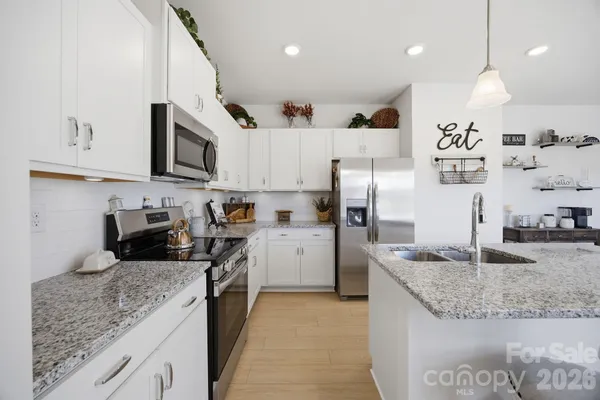 a kitchen with granite countertop a sink a counter top space stainless steel appliances and cabinets