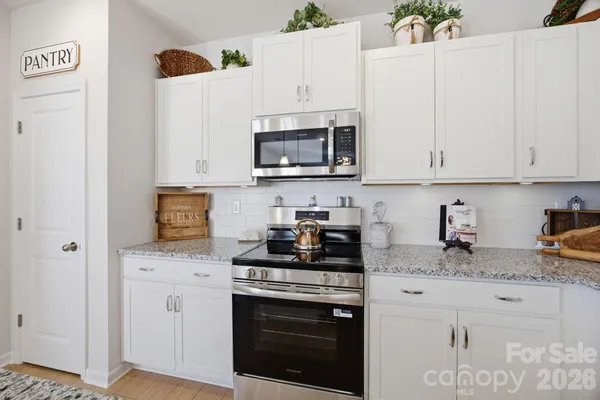 a kitchen with granite countertop white cabinets and white appliances