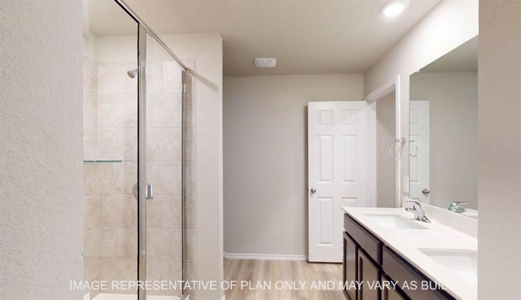 3112 Cyprian Road Lorena, TX 76655 - Photo 13 of 20 Spa-inspired primary bathroom featuring a frameless glass shower enclosure with tile surround, dual-sink vanity with wood-finish cabinetry and white quartz countertop, large mirror with integrated lighting, and neutral tile flooring throughout