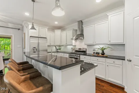 a kitchen with stainless steel appliances granite countertop a stove a sink a dining table and chairs with wooden floor