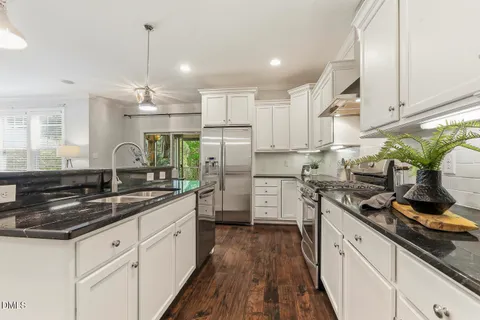 a living room with couches and kitchen view with wooden floor