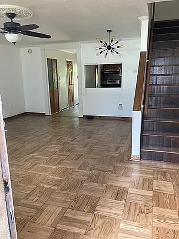 1087 Blake Avenue Brooklyn, NY 11208 - Photo 2 of 16 Spare room with stairs, ceiling fan with notable chandelier, and baseboards