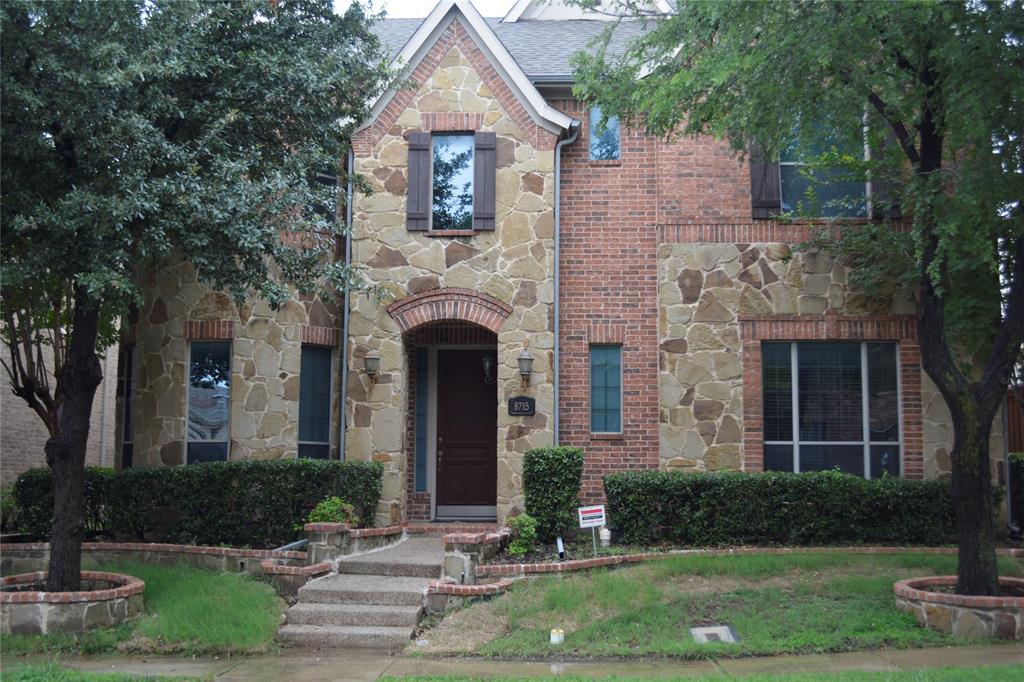 8715 Lost Canyon Road Irving, TX 75063 - Photo 2 of 4 Stone and brick facade featuring an arched entryway, decorative window shutters, and a concrete pathway