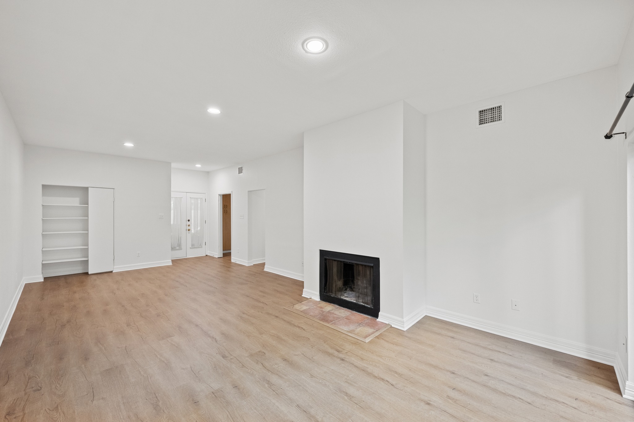 409 East 38th Street, Unit 101 Austin, TX 78705 - Photo 7 of 27 A well-proportioned living space features light-toned flooring and a cozy fireplace with a tiled hearth.
