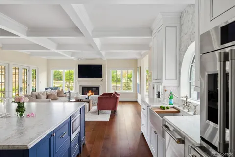 a living room with stainless steel appliances furniture a flat screen tv and a large window