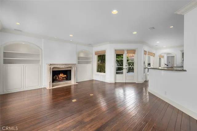 an empty room with wooden floor a fireplace and windows