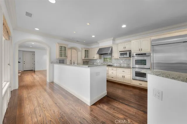 a large kitchen with white cabinets and wooden floors