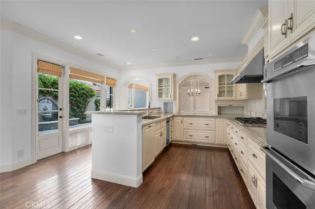 a large kitchen with granite countertop a large stove a sink dishwasher and white cabinets with wooden floor