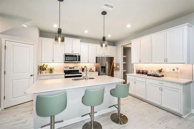 a kitchen with white cabinets stainless steel appliances and a dining table