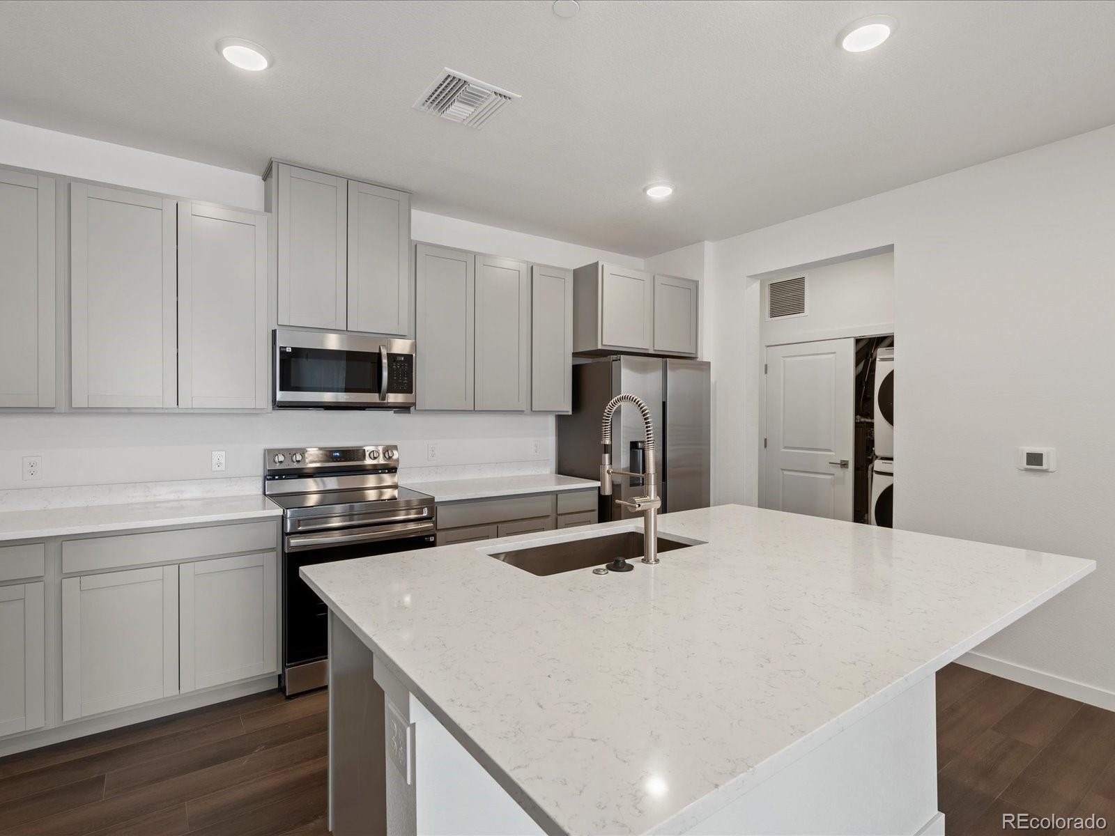 6153 North Ceylon Street, Unit 304 Denver, CO 80249 - Photo 3 of 14 a kitchen with stainless steel appliances a sink stove refrigerator and cabinets