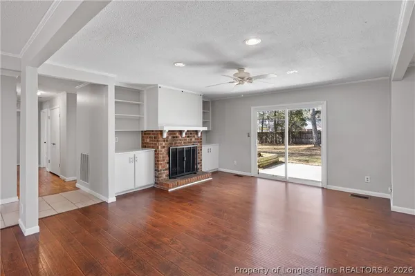 a view of an empty room with wooden floor and a fireplace