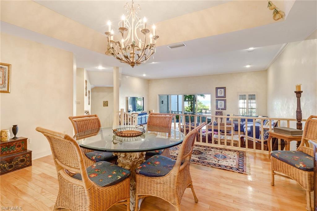 74 Seagate Drive, Unit 4 Naples, FL 34103 - Photo 11 of 35 a view of a dining room with furniture a chandelier and wooden floor