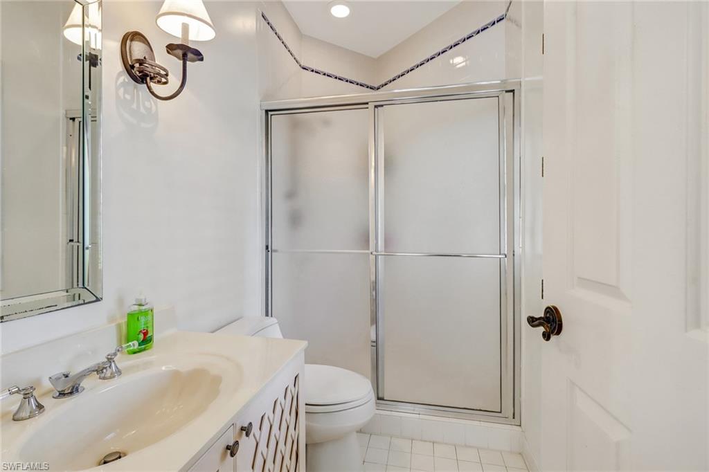 74 Seagate Drive, Unit 4 Naples, FL 34103 - Photo 24 of 35 a bathroom with a granite countertop sink a toilet and shower