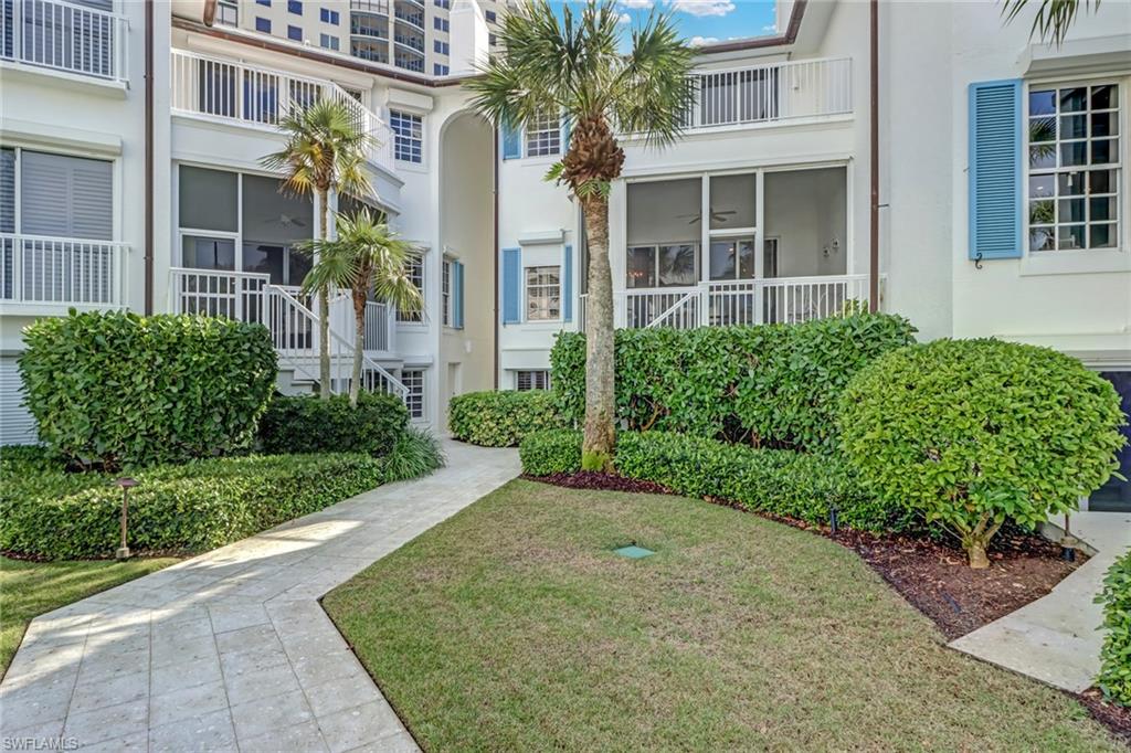 74 Seagate Drive, Unit 4 Naples, FL 34103 - Photo 33 of 35 front view of a brick house with a yard