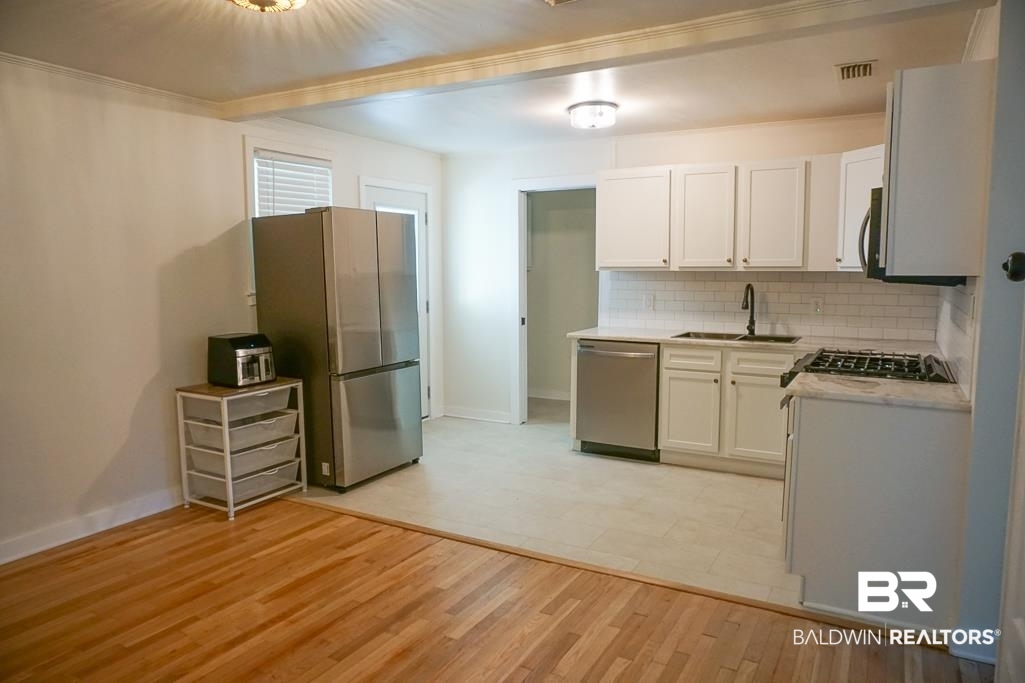 4667 Cottonwood Drive Mobile, AL 36608 - Photo 6 of 21 Kitchen with appliances with stainless steel finishes, light wood-type flooring, backsplash, sink, and white cabinetry
