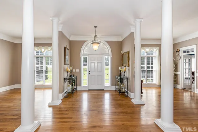 a hallway with wooden floor chandelier and windows