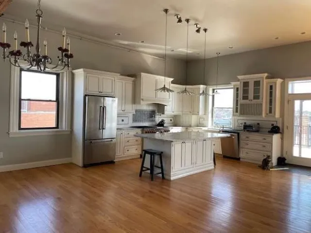 a kitchen with a refrigerator a sink dishwasher a stove and white cabinets with wooden floor