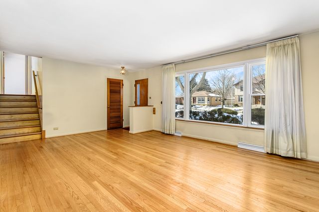 a view of an empty room with a window and a kitchen area